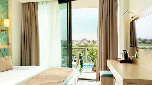 Hotelværelse med altan og udsigt over poolområdet. (AI-genereret tekst)