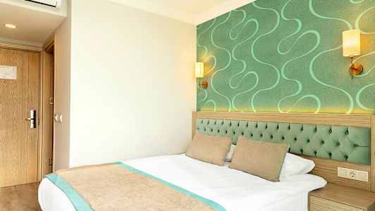 Hotelværelse med grønne detaljer og en seng. (AI-genereret tekst)