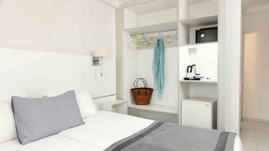 Hotelværelse med seng, garderobe og en minikøleskab. (AI-genereret tekst)