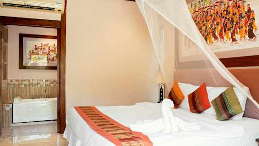 Soveværelse med dekorativt myggenet over en dobbeltseng, farverige puder og kunst på væggene. (AI-genereret tekst)