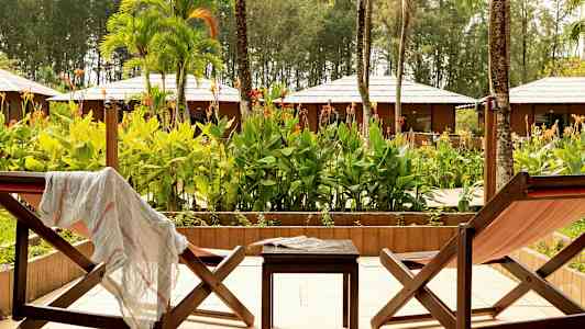 To liggestole og et bord på en terrasse med udsigt over en have. (AI-genereret tekst)