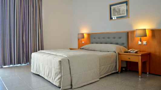 Hotelværelse med en seng og to sengelamper. (AI-genereret tekst)