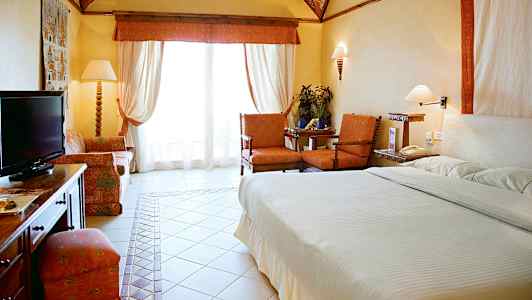 Et hotelværelse med seng, siddeområde og en TV. (AI-genereret tekst)