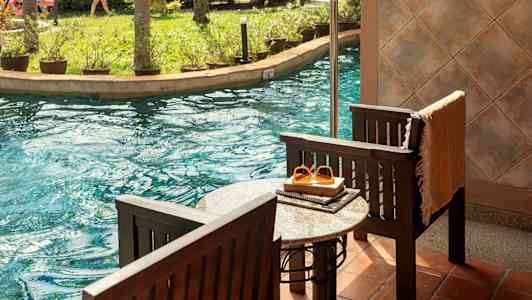 Terrasse ved poolen med udsigt til en have og vandrutsjebane. (AI-genereret tekst)