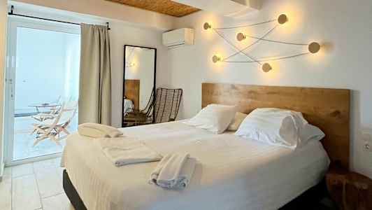 Billede af et hotelværelse med en dobbeltseng, træindretning og moderne belysningsarmaturer på væggen. (AI-genereret tekst)