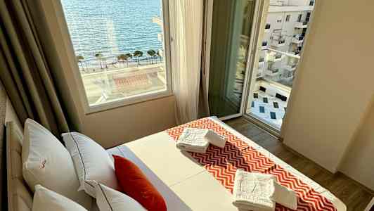 Et hotelværelse med en seng, vindue med havudsigt og håndklæder på sengen. (AI-genereret tekst)