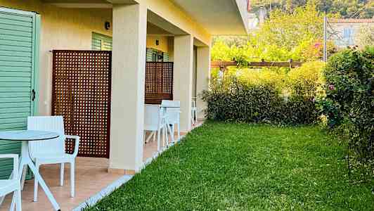 Udvendigt billede af en bygning med græsplæne og siddepladser udenfor. (AI-genereret tekst)