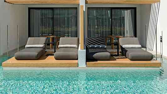 Luksuriøse liggestole ved en pool foran moderne hotelværelser. (AI-genereret tekst)