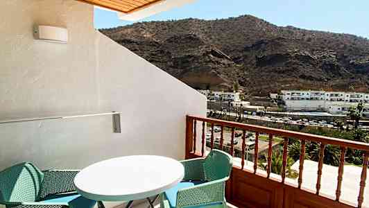 En altan med møbler og udsigt til bjerge. (AI-genereret tekst)