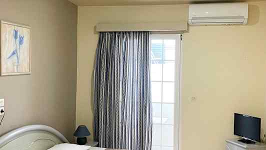 Hotelværelse med to enkeltsenge, et fjernsyn og et vindue med gardiner. (AI-genereret tekst)