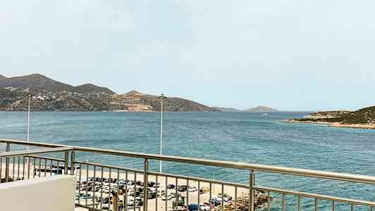 Udsigt fra en balkon mod havet med bjerge i baggrunden. (AI-genereret tekst)