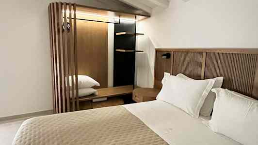 Et soveværelse med en dobbeltseng, hvid loftspanel og et træskab. (AI-genereret tekst)