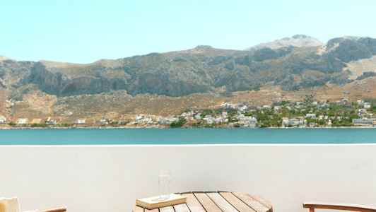 To stole og et bord på en altan med udsigt over en sø og bjerge. (AI-genereret tekst)