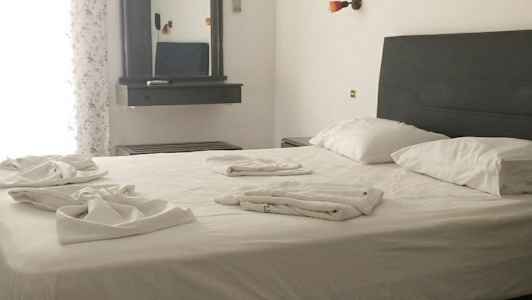 Et soveværelse med en dobbeltseng, sengetøj set på sengen. Et spejl hænger på væggen ved siden af. (AI-genereret tekst)