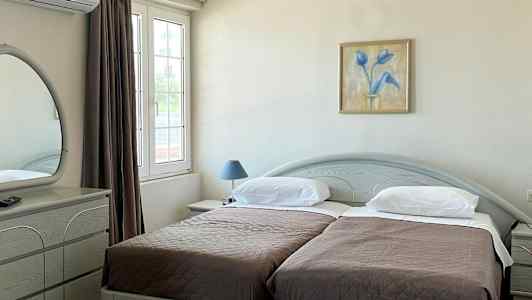 Hotelværelse med to enkeltsenge, et skrivebord og et spejl. (AI-genereret tekst)