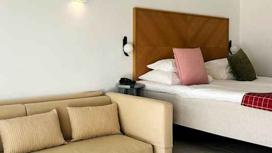 Et hotelværelse med seng og sofa samt et bord. (AI-genereret tekst)