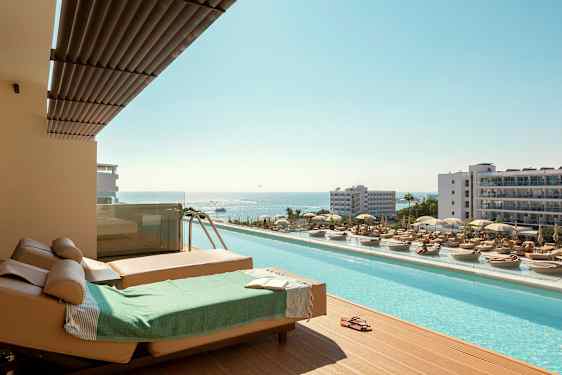 Liggestole og pool med udsigt over havet i en feriested. (AI-genereret tekst)