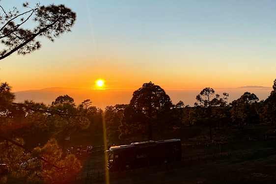 Billede af en solnedgang over en skov med et køretøj i forgrunden. (AI-genereret tekst)
