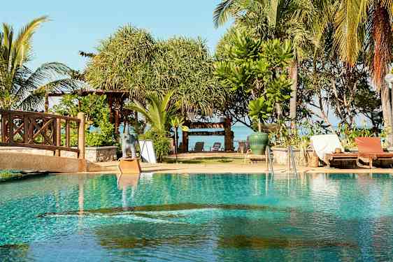 En pool med solsenge ved siden af, og bagved er der træer og et skilt med teksten 'Lanta Villa'. (AI-genereret tekst)