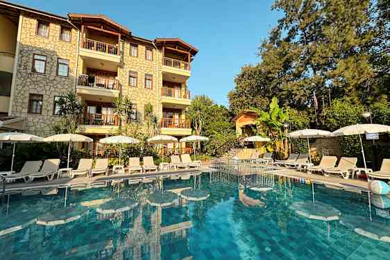 Billede af hotelfacade med pool og liggestole foran. (AI-genereret tekst)