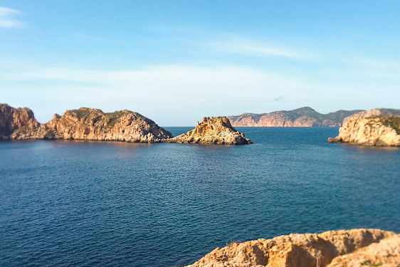 Kystlandskab med klippeøer i havet under en klar blå himmel. (AI-genereret tekst)