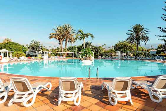 En stor pool omgivet af liggestole og palmer. (AI-genereret tekst)