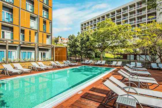 En pool med solsenge og bygninger i baggrunden. (AI-genereret tekst)