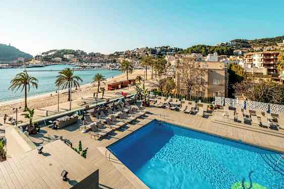 Udendørs pool med liggestole og udsigt til stranden og en havn. (AI-genereret tekst)