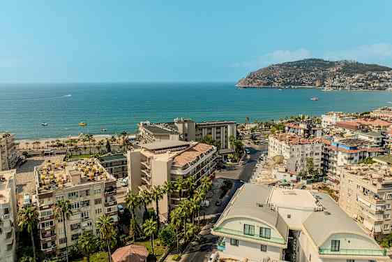 Udsigt over en kystby med bygninger, strand og hav. (AI-genereret tekst)