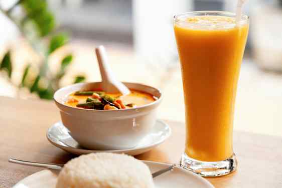 En skål med gul karry, en tallerken med ris og et glas med gul drik. (AI-genereret tekst)