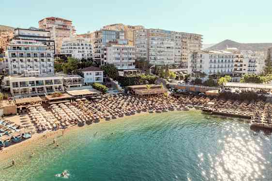 Hoteller og parasoller ved en strand med klart vand. (AI-genereret tekst)