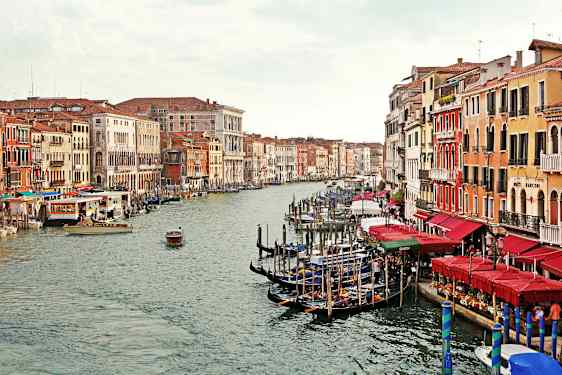 En kanal med gondoler og farverige bygninger på begge sider i Venedig. (AI-genereret tekst)