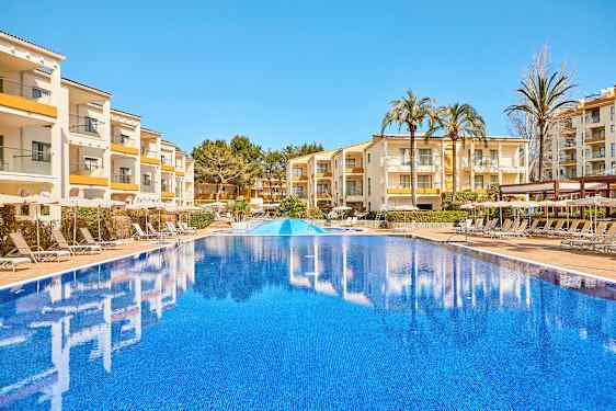 Billede af en udendørs pool med bygninger og liggestole i baggrunden. (AI-genereret tekst)