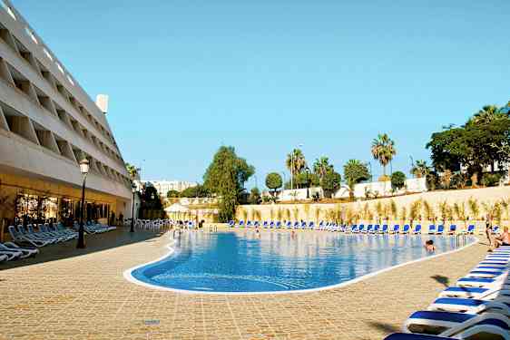 En hotelpool med liggestole rundt omkring. (AI-genereret tekst)