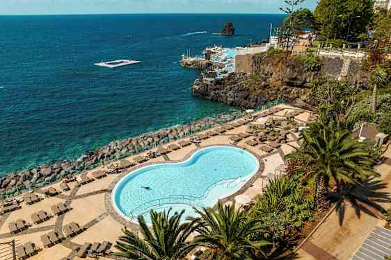 Lukket pool med liggestole og udsigt over havet. (AI-genereret tekst)