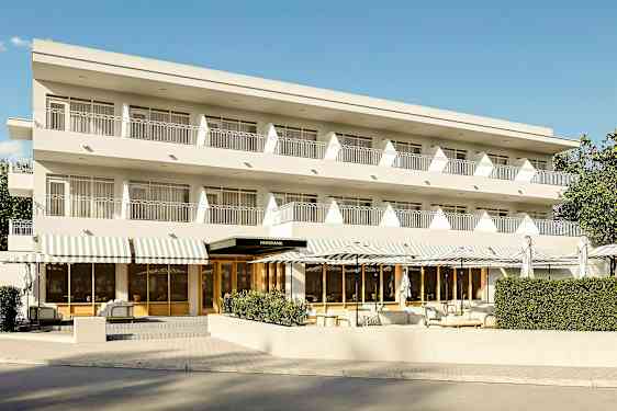 Tre etagers bygning med altaner og indgang med hvide markiser. (AI-genereret tekst)