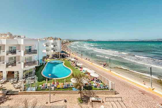 Hotelbygning og poolområde ved strandpromenade og sandstrand. (AI-genereret tekst)