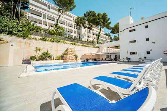 Liggestole ved en pool med hotelbygning i baggrunden. (AI-genereret tekst)