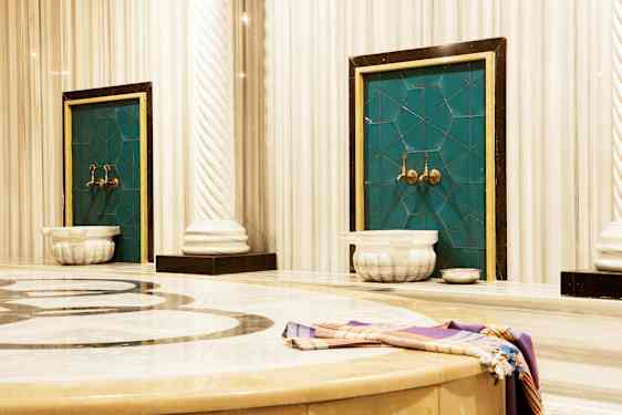 Billede af et traditionelt hamam med marmorerede overflader og vandhaner. (AI-genereret tekst)