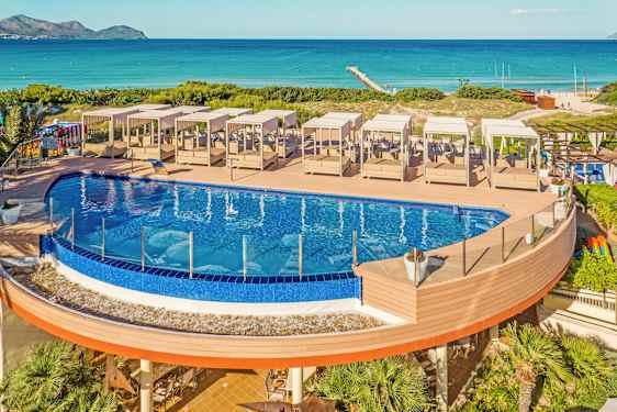 Udendørs pool med solsenge på en træterrasse tæt på stranden. (AI-genereret tekst)