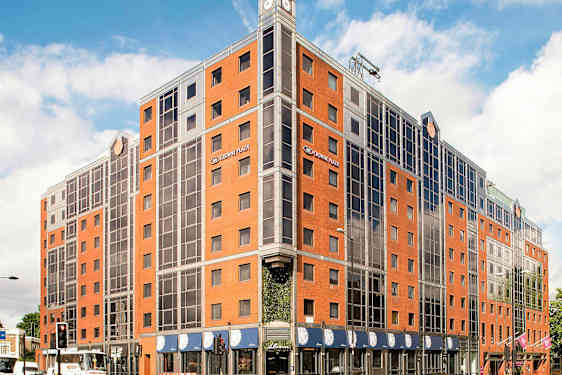 Billede af et hotel med røde mursten og glasvinduer. (AI-genereret tekst)