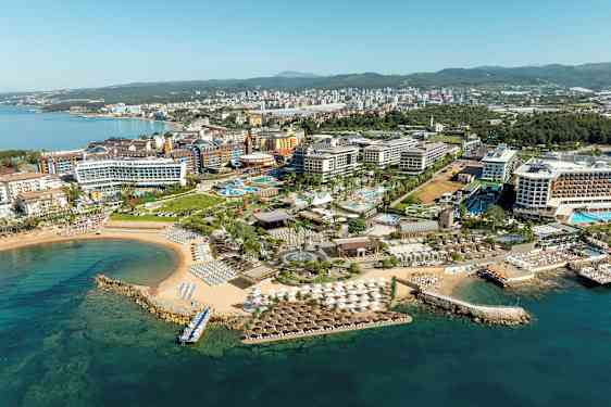 Luftfoto af en ferieby ved kysten med hoteller, swimmingpools og strand. (AI-genereret tekst)