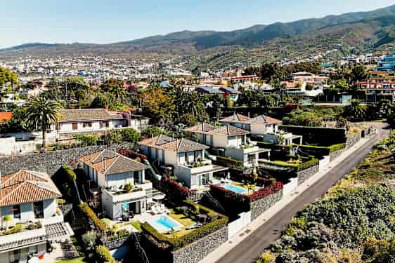 Billede af et område med moderne huse og små pools omgivet af grønt og en vej. (AI-genereret tekst)