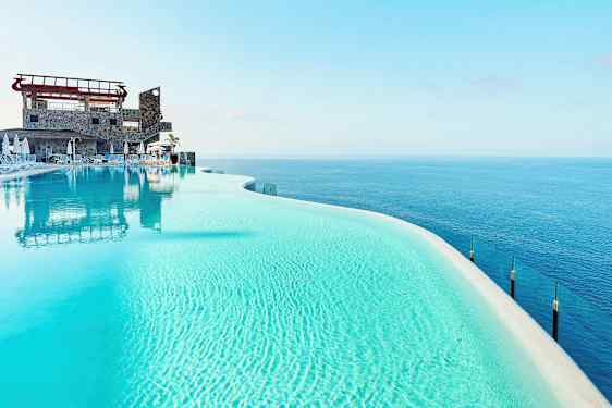 Infinitypool med klart blåt vand og udsigt over havet. (AI-genereret tekst)