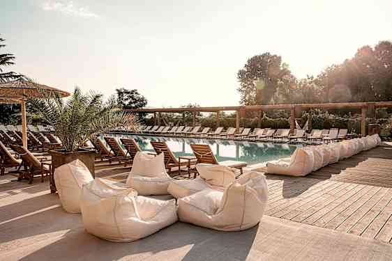 En udendørs pool omgivet af solsenge og sækkestole. (AI-genereret tekst)