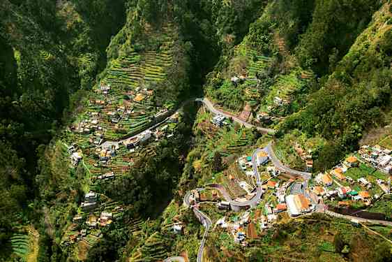 Udsigt over en dal med terrasserede landbrugsområder og huse. (AI-genereret tekst)