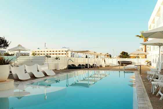 Udendørs pool med liggestole og parasoller ved hotellet. (AI-genereret tekst)