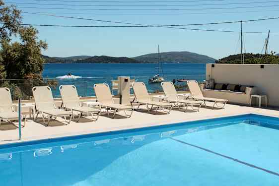 Swimmingpool med liggestole og havudsigt i baggrunden. (AI-genereret tekst)