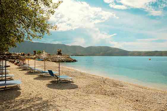 Strand med liggestole og parasoller ved havet. (AI-genereret tekst)