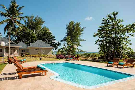 Stor billede af en pool omgivet af liggestole ved en kompleks. (AI-genereret tekst)